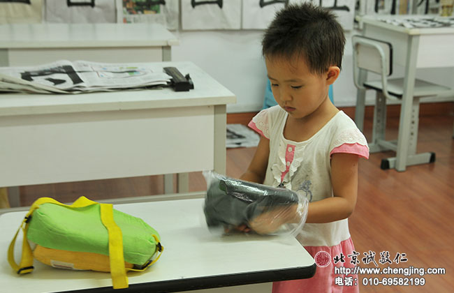 寫完書法自己收拾文房四寶，將毛氈疊放整齊塞入袋子中。